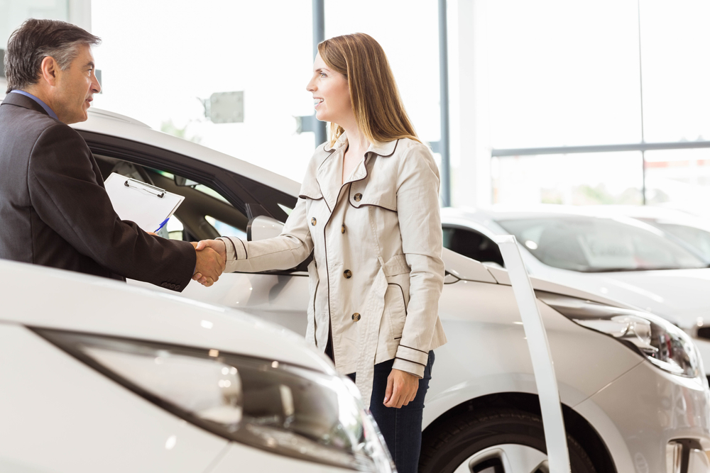 Salesman shaking hand of a client at new car showroom